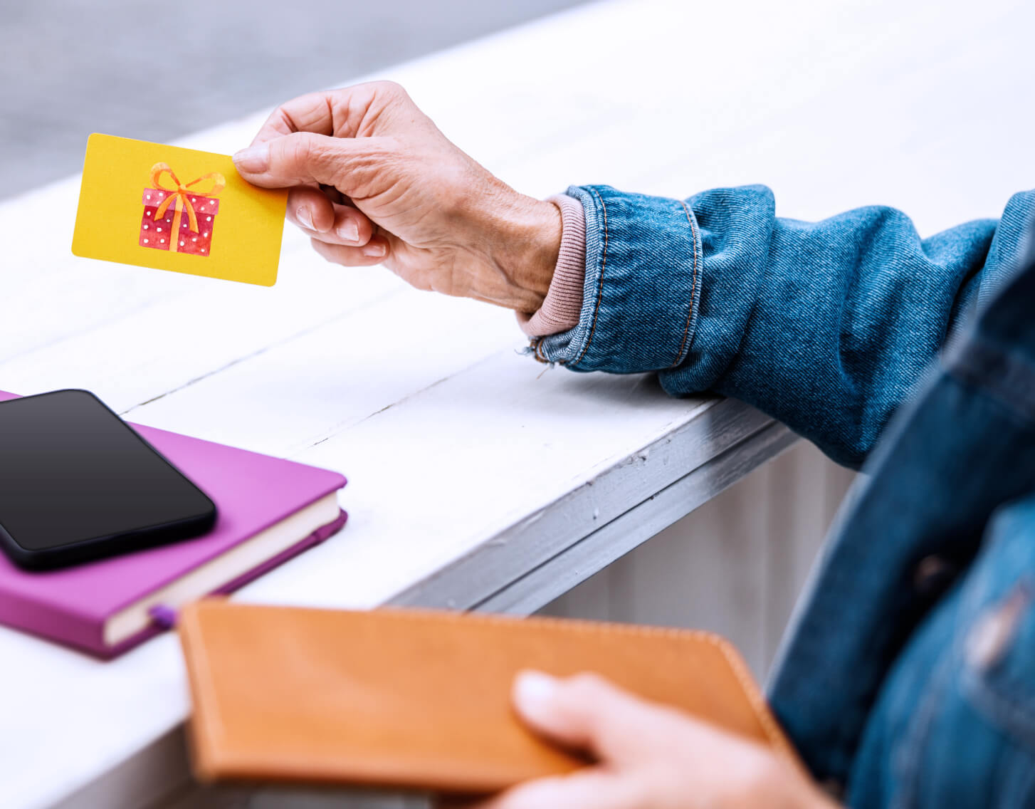 person handing a gift card to the cashier to make a purchase