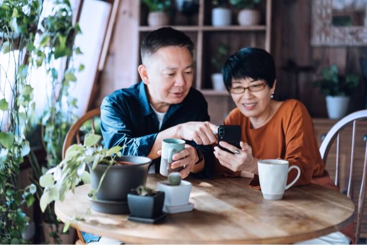 Man and woman looking at the Experien Credit Center app on a phone while sitting at a table