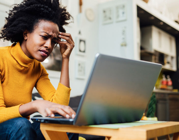 Woman sitting down with a confused expression while looking at her laptop